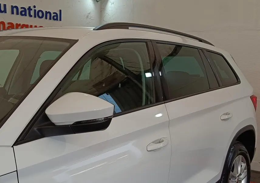 Vue de côté droit du SUV SKODA KODIAQ blanc 2022, mettant en valeur les rétroviseurs et les barres de toit noires.