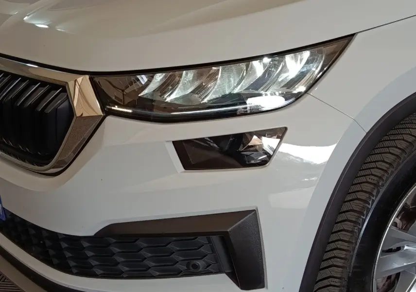 Gros plan sur l’avant droit blanc du Skoda Kodiaq 2022, mettant en valeur le phare LED et la calandre noire.
