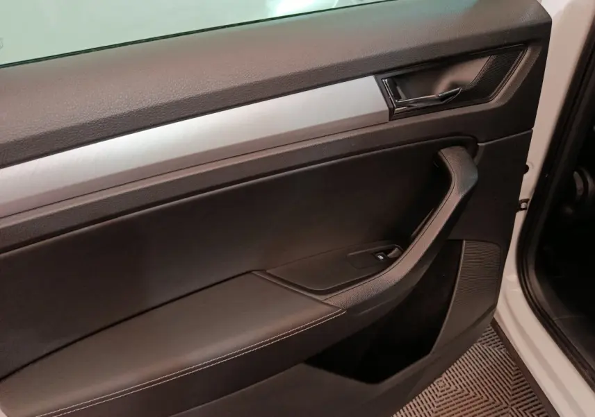 Gros plan sur la porte intérieure côté conducteur du Skoda Kodiaq blanc, avec garniture noire et insert aluminium brossé.