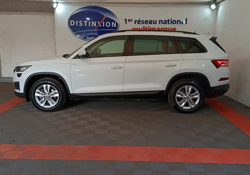 Vue de profil côté gauche d’un Skoda Kodiaq blanc 7 places, stationné en intérieur avec jantes alliage.