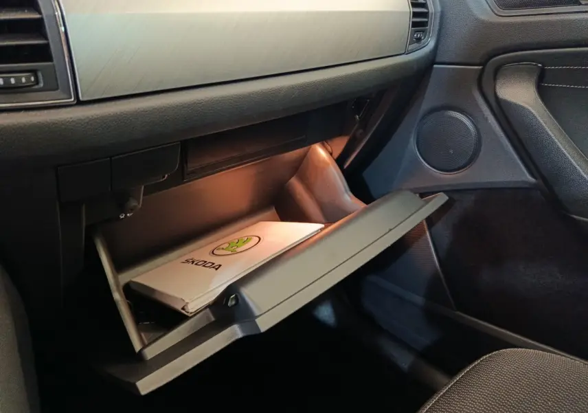 Intérieur du Skoda Kodiaq 2022, vue côté passager sur la boîte à gants ouverte avec manuel Skoda visible.