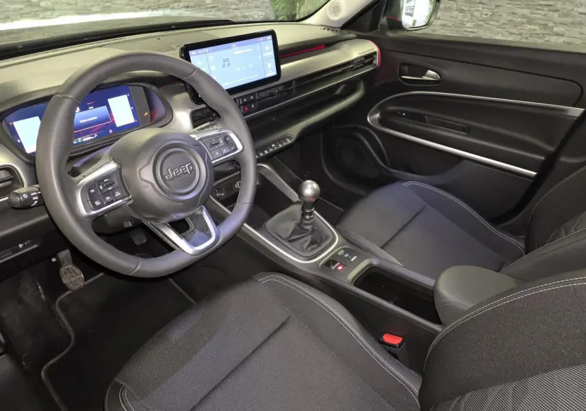 Vue intérieure côté conducteur du Jeep Avenger 2025 noir, avec tableau de bord numérique et écran tactile central.