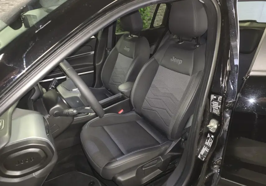 Vue intérieure côté conducteur du Jeep Avenger noir 2025, sièges mixtes tissu/TEP avec logo Jeep brodé.