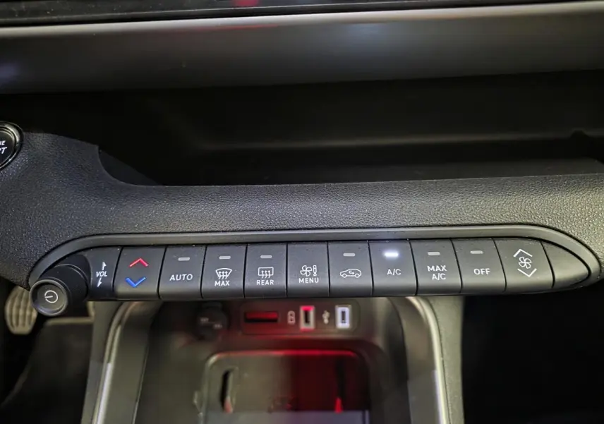Vue rapprochée de la console centrale du Jeep Avenger noir 2025, montrant les commandes de climatisation et volume.