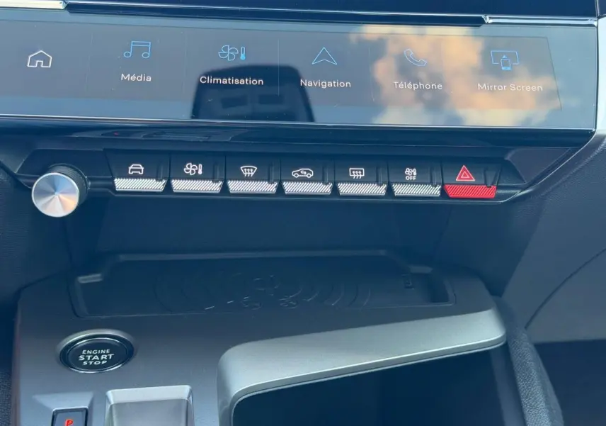 Vue rapprochée de la console centrale de la Peugeot 308 rouge, montrant les commandes tactiles et le bouton start/stop.