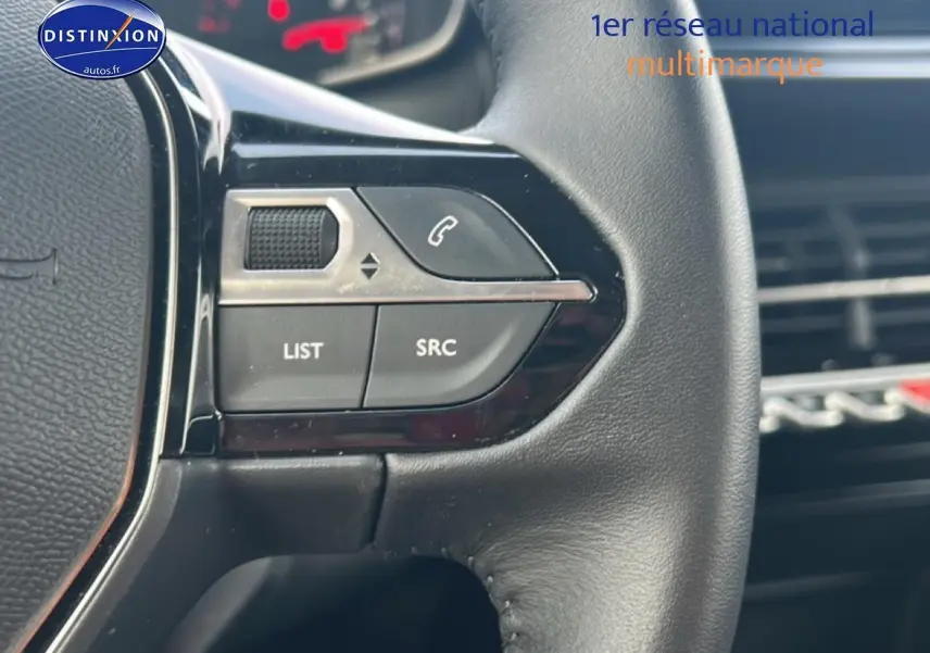 Gros plan sur les commandes audio au volant noir du Peugeot 208 1.2 100 style gris artense, intérieur moderne.
