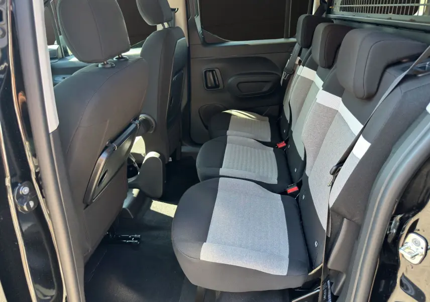 Vue intérieure côté droit sur la banquette arrière tissu gris et noir du Citroën Berlingo noir 2025 avec portes coulissantes ouvertes.
