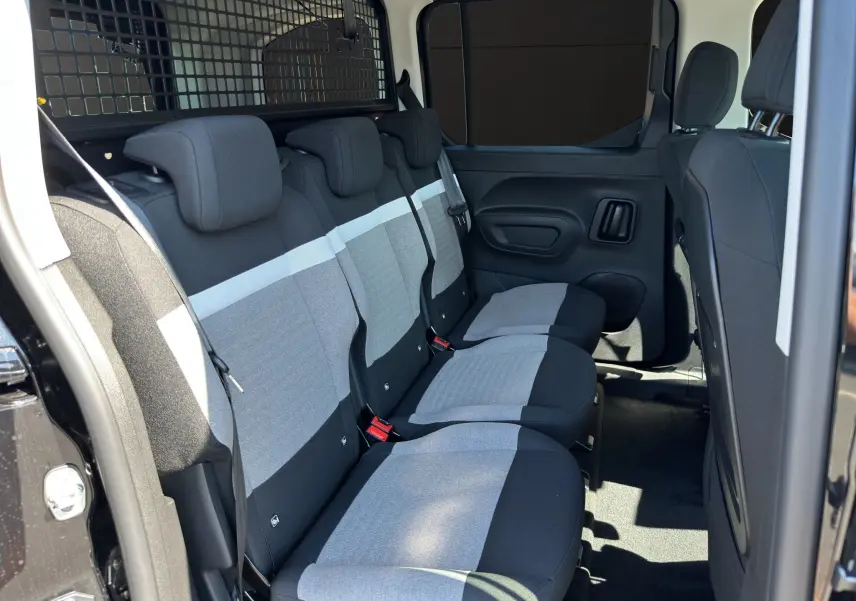 Vue intérieure côté droit des sièges arrière gris et noirs du Citroën Berlingo N1 BlueHDi 130 2025 avec cloison de séparation noire.