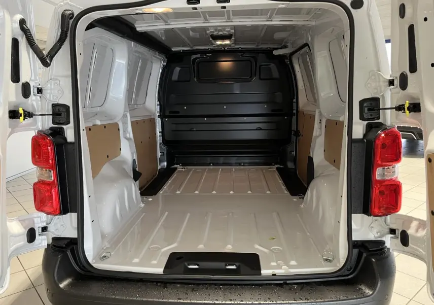 Vue arrière ouverte du Peugeot Expert Fourgon blanc 2024 montrant l’espace de chargement vide avec panneaux latéraux en bois.