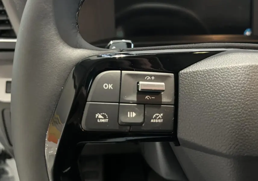 Gros plan sur les commandes gauche du volant en cuir noir du Peugeot Expert Fourgon blanc 2024.