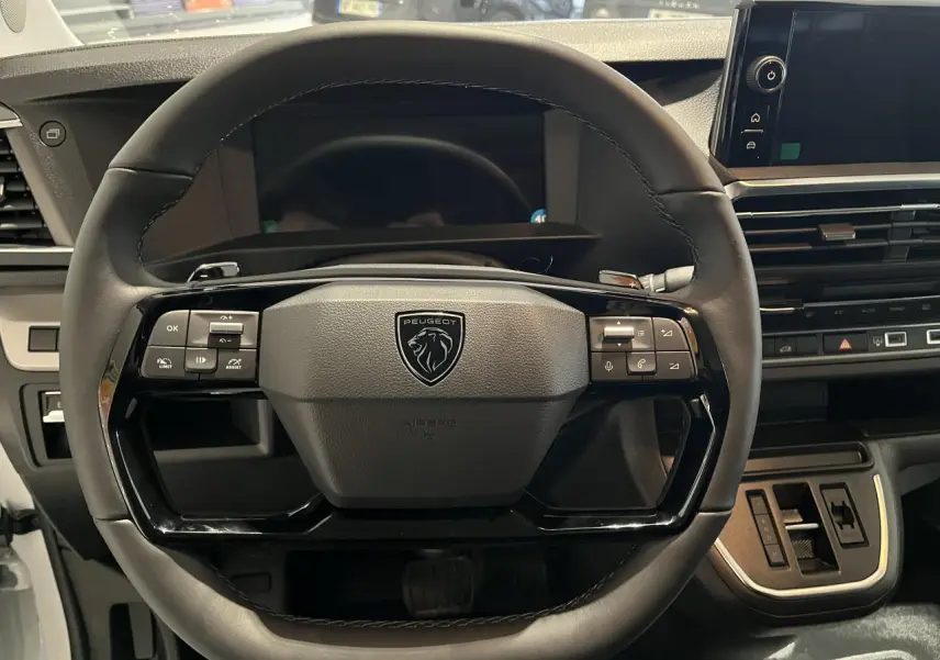 Vue rapprochée du volant en cuir noir du Peugeot Expert Fourgon 2024 avec commandes intégrées et tableau de bord numérique.