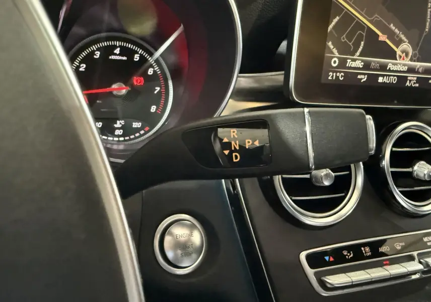 Gros plan sur la commande de boîte automatique et le tableau de bord noir d’un Mercedes GLC 250 Fascination 2019.