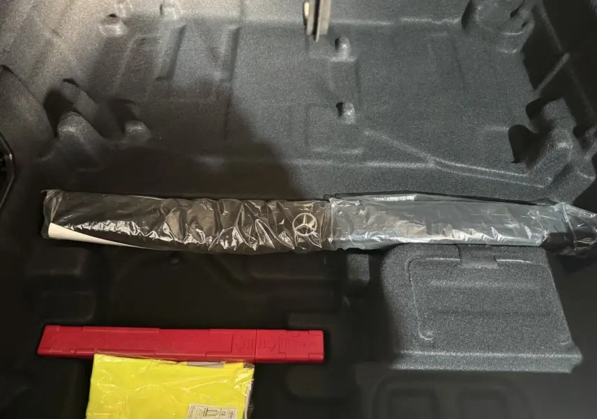 Vue intérieure du coffre d'un Mercedes GLC 250 Fascination 2019 gris foncé, avec un outil Mercedes emballé et un triangle de signalisation rouge.