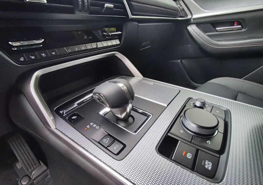 Gros plan sur la console centrale côté conducteur du Mazda CX-60 blanc métal 2024 avec levier de vitesse et commandes intégrées.