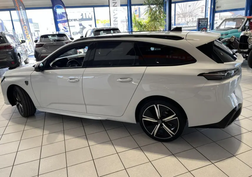 Peugeot 308 SW BlueHDi 130ch GT blanc okenite vue de profil côté gauche en intérieur showroom.
