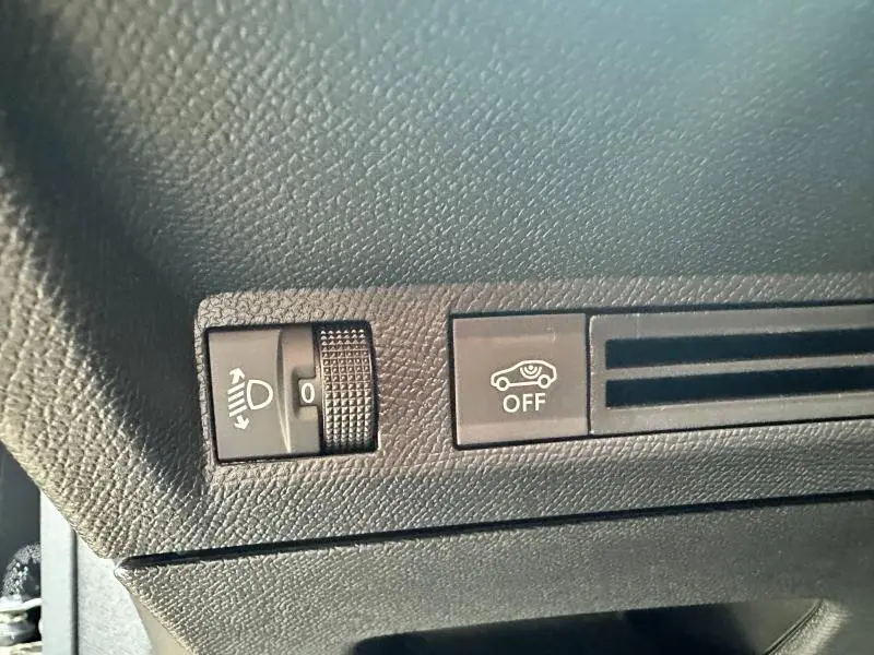 Gros plan sur les commandes noires du tableau de bord côté gauche du Peugeot 3008 noir Perla Nera, avec réglage phare et bouton OFF.