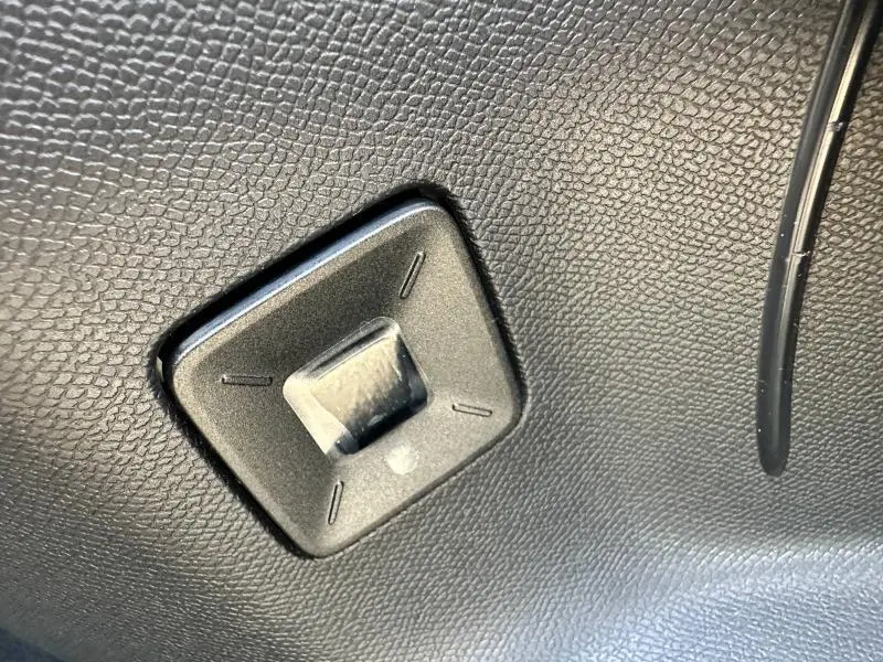Détail du bouton de réglage en plastique noir sur le revêtement intérieur texturé du Peugeot 3008 Hybrid 2025.