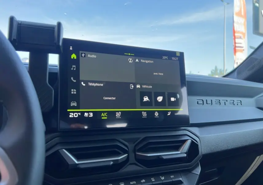 Intérieur du Dacia Duster 2025 blanc glacier, vue du tableau de bord avec écran tactile et aérateurs hexagonaux.
