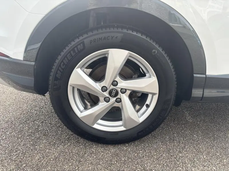 Gros plan sur la roue arrière droite d'un Audi Q3 blanc Glacier métallisé avec jante alu 5 branches et pneu Michelin Primacy 4.