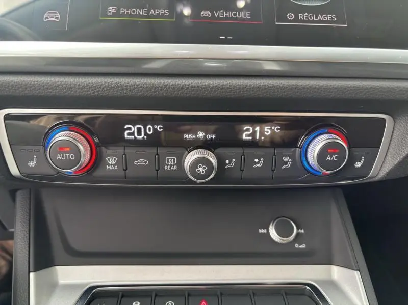 Vue rapprochée du panneau de climatisation bi-zone avec réglages numériques sur Audi Q3 blanc Glacier 2022.