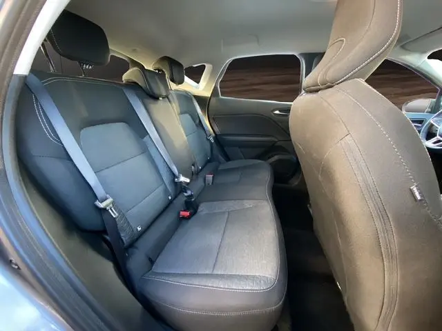 Vue intérieure arrière du Renault Captur gris Cassiopée 2023, sièges tissu gris foncé avec ceintures de sécurité visibles.