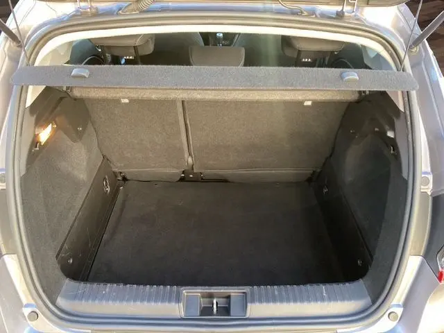 Coffre ouvert vu de l'arrière d'un Renault Captur gris Cassiopée 2023, espace de chargement vide et tapis noir.