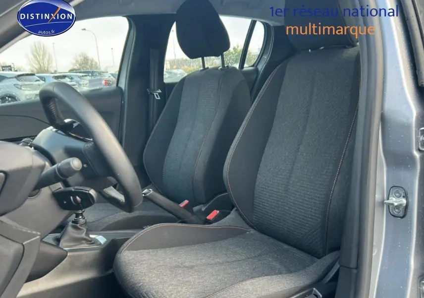 Vue intérieure côté gauche de la Peugeot 208 1.2 100 Style gris artense, montrant sièges tissu et levier de vitesse manuel.