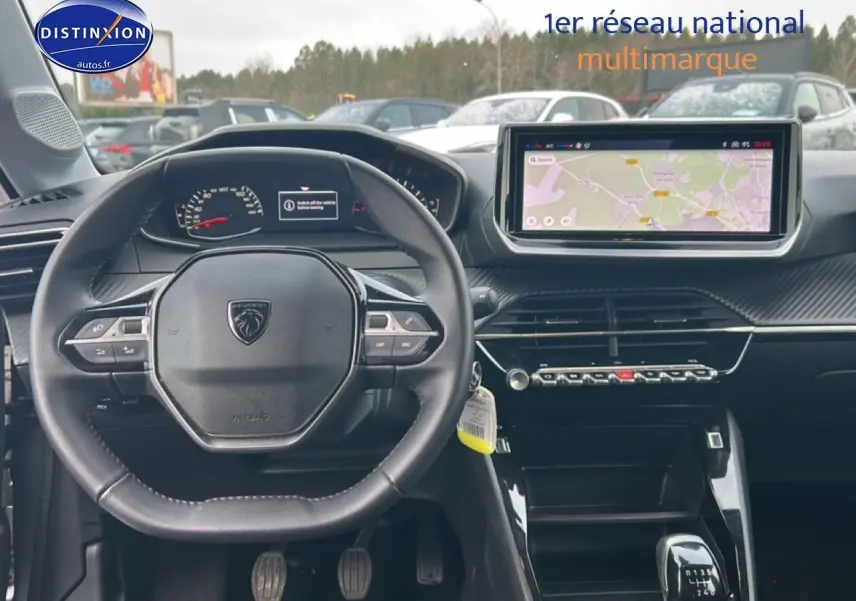 Vue intérieure centrée sur le volant et tableau de bord de la Peugeot 208 1.2 100 style essence gris artense, avec écran tactile et boîte manuelle.