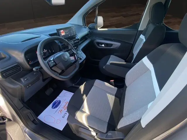 Vue intérieure côté conducteur du Citroën Berlingo 2025 gris Artense, montrant sièges tissu bicolore et tableau de bord moderne.