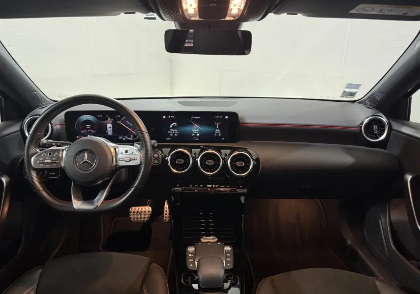 Vue intérieure frontale du tableau de bord et volant cuir alu de la Mercedes Classe A 200 AMG Line 2021, avec écrans numériques larges.
