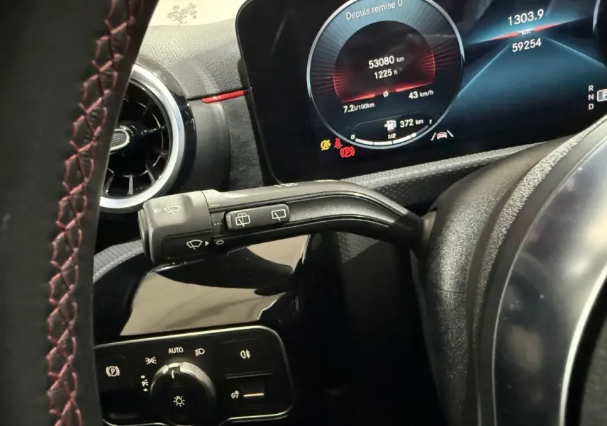 Gros plan sur le tableau de bord et levier d’essuie-glace d’une Mercedes Classe A A 200 AMG Line 2021, intérieur noir avec surpiqûres rouges.