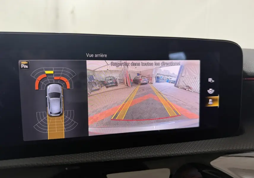 Écran multimédia de la Mercedes Classe A 200 AMG Line montrant la caméra de recul et l'aide au stationnement active.