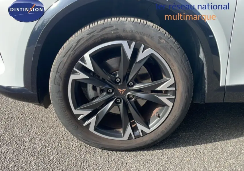 Gros plan sur la roue avant droite du CUPRA Formentor blanc neige métal avec jante alliage noire et argentée.