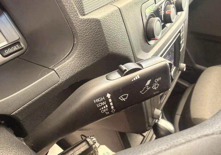 Gros plan sur la manette d’essuie-glace noire dans l’habitacle du Volkswagen Caddy 2019, avec tableau de bord gris.