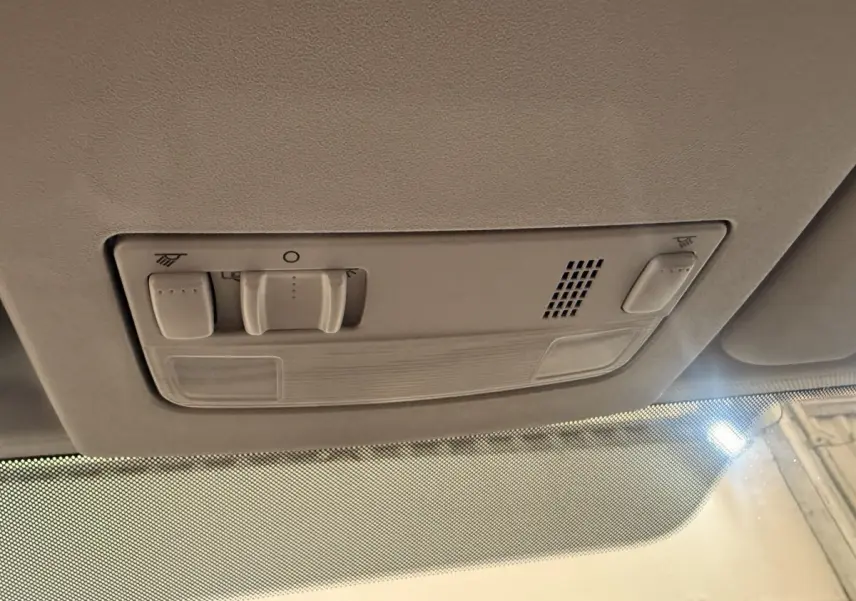 Plafonnier intérieur beige avec commandes d’éclairage et ventilation, vue depuis l’habitacle avant du Volkswagen Caddy noir.