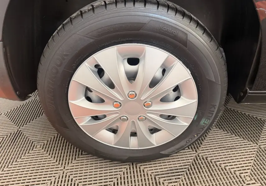 Gros plan sur la roue avant droite du Volkswagen Caddy noir, avec jante acier et enjoliveur argenté.