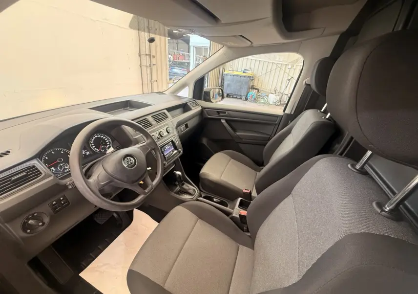Vue intérieure avant droite du Volkswagen Caddy 2019, sièges gris et tableau de bord avec écran tactile.