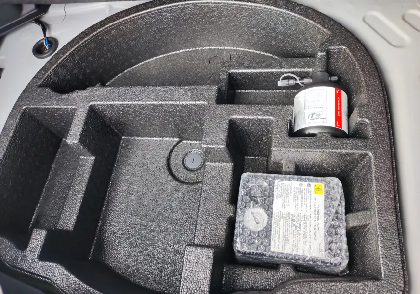 Rangement en mousse noire dans le coffre de la Mazda2 Hybrid 2024, avec kit de réparation pneus visible.