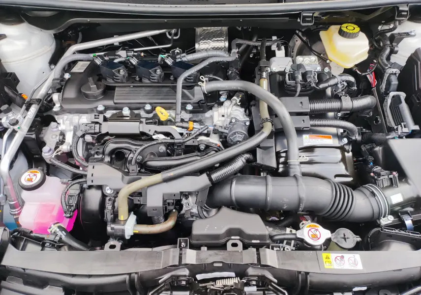 Moteur essence hybride de la Mazda2 2024 blanc métallisé vu de dessus avec composants et réservoirs visibles.