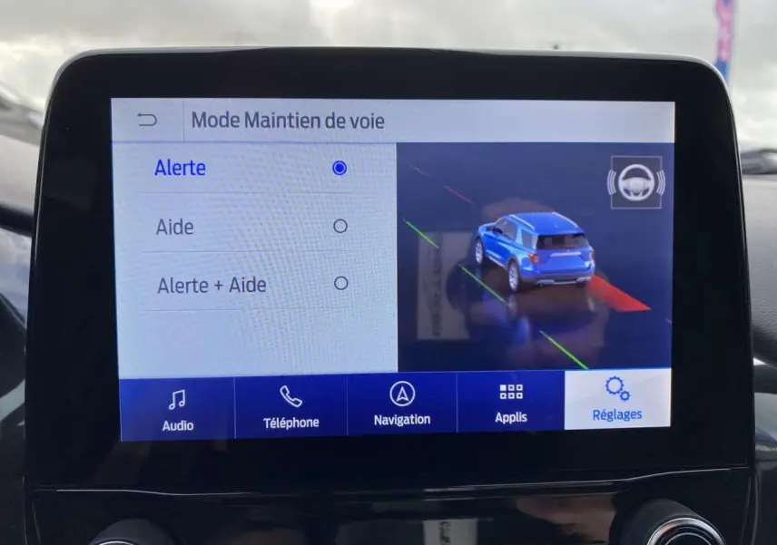 Écran tactile intérieur montrant le mode maintien de voie avec une voiture bleue en vue arrière sur l'affichage.