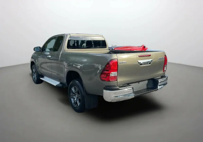 Toyota Hilux 4x4 2025 en bronze impérial, vue 3/4 arrière droit avec benne et jantes alliage visibles.