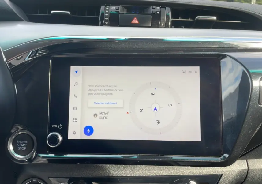 Écran tactile central du Toyota Hilux 2025 affichant une boussole, entouré de commandes noires brillantes.