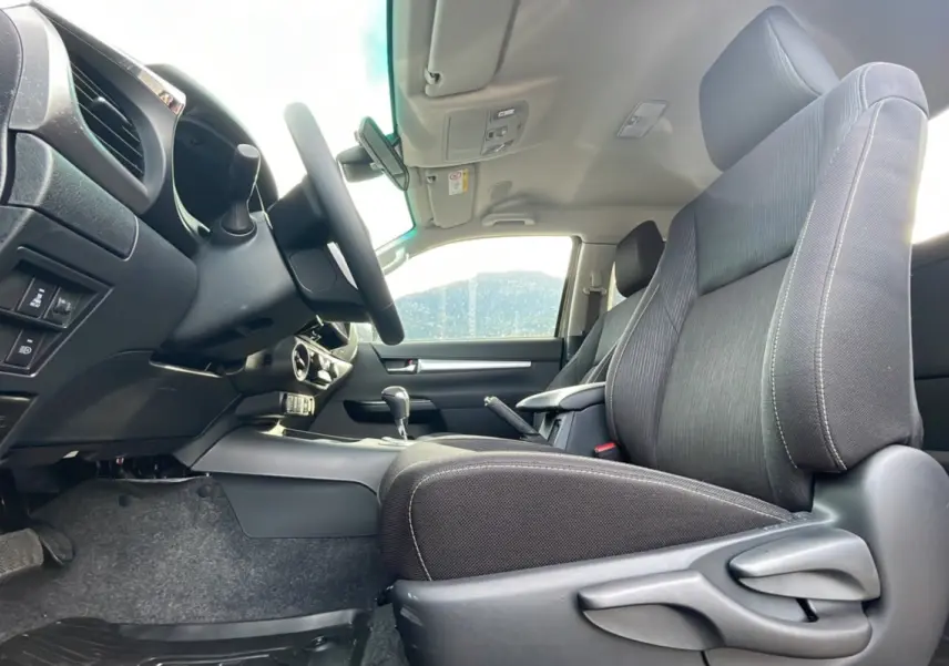 Intérieur du Toyota Hilux 4x4 2025 vu côté conducteur, sièges noirs et tableau de bord moderne.
