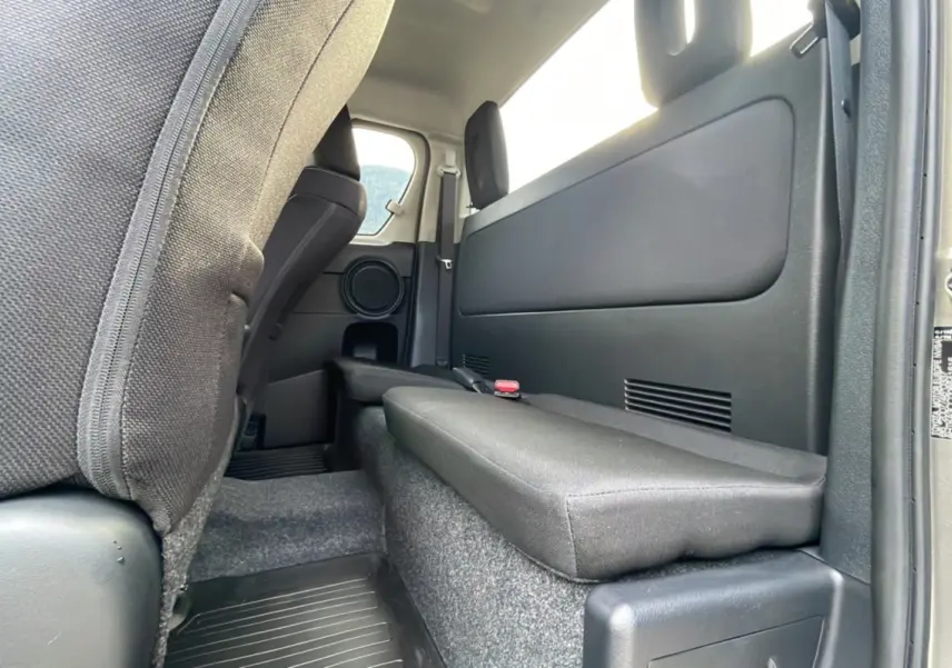 Vue intérieure arrière côté droit du Toyota Hilux 4x4 2025, avec banquette rabattue et garniture noire.
