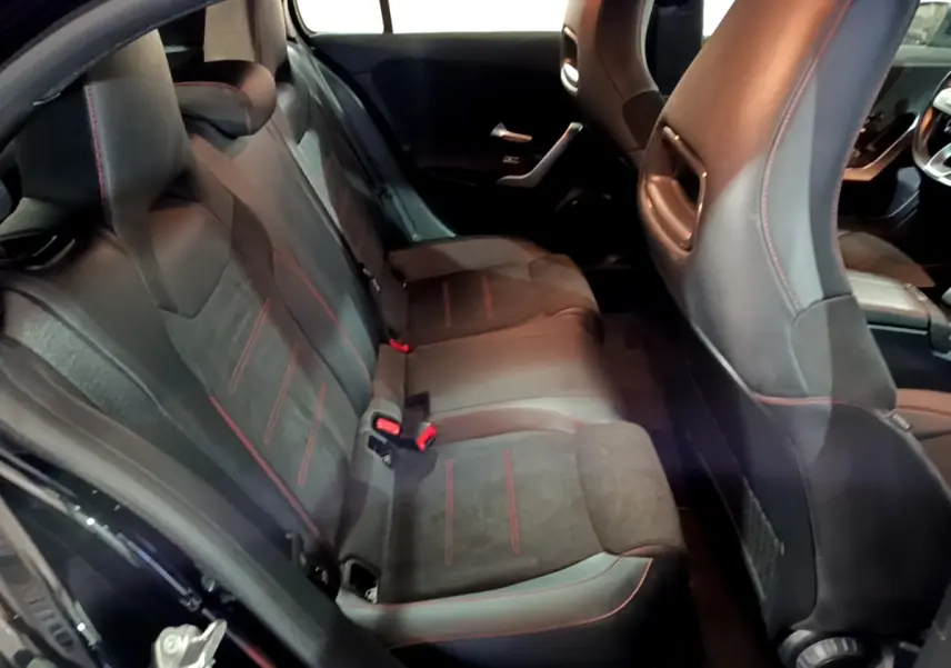 Vue intérieure arrière côté gauche de la Mercedes Classe A 200 AMG Line 2021, sièges noirs avec surpiqûres rouges.