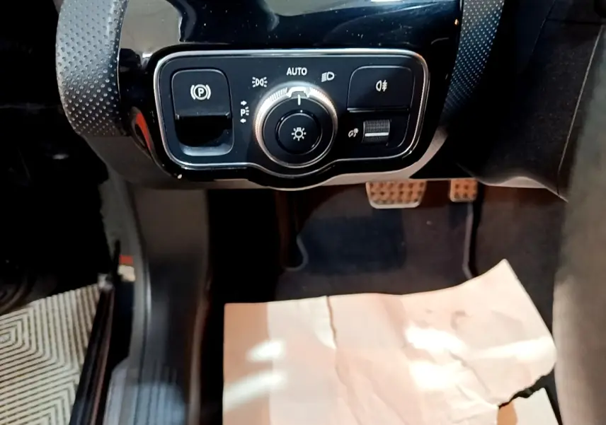 Gros plan sur les commandes d’éclairage et frein à main électrique dans l’habitacle noir d’une Mercedes Classe A A 200 AMG Line.