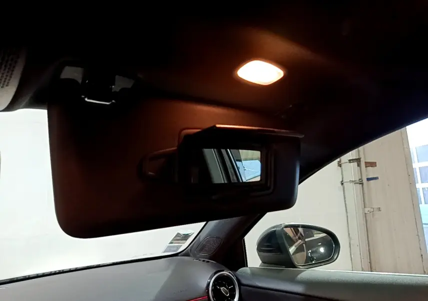 Intérieur noir de la Mercedes Classe A 200 AMG Line 2021, vue sur pare-soleil avec miroir et rétroviseur côté gauche.