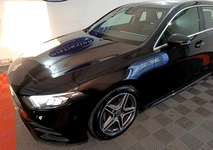 Mercedes Classe A 200 AMG Line noire vue 3/4 avant droit, mettant en valeur ses jantes alliage et phares LED distinctifs.