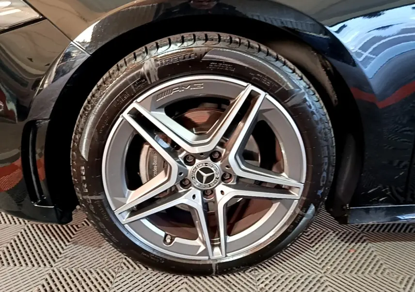 Gros plan sur la roue avant gauche noire d'une Mercedes Classe A 200 AMG Line avec jante AMG cinq branches.