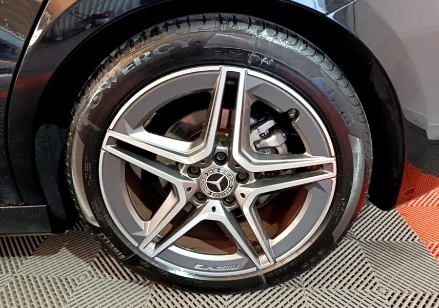 Gros plan sur la roue avant droite noire d'une Mercedes Classe A 200 AMG Line avec jante alliage AMG cinq branches.